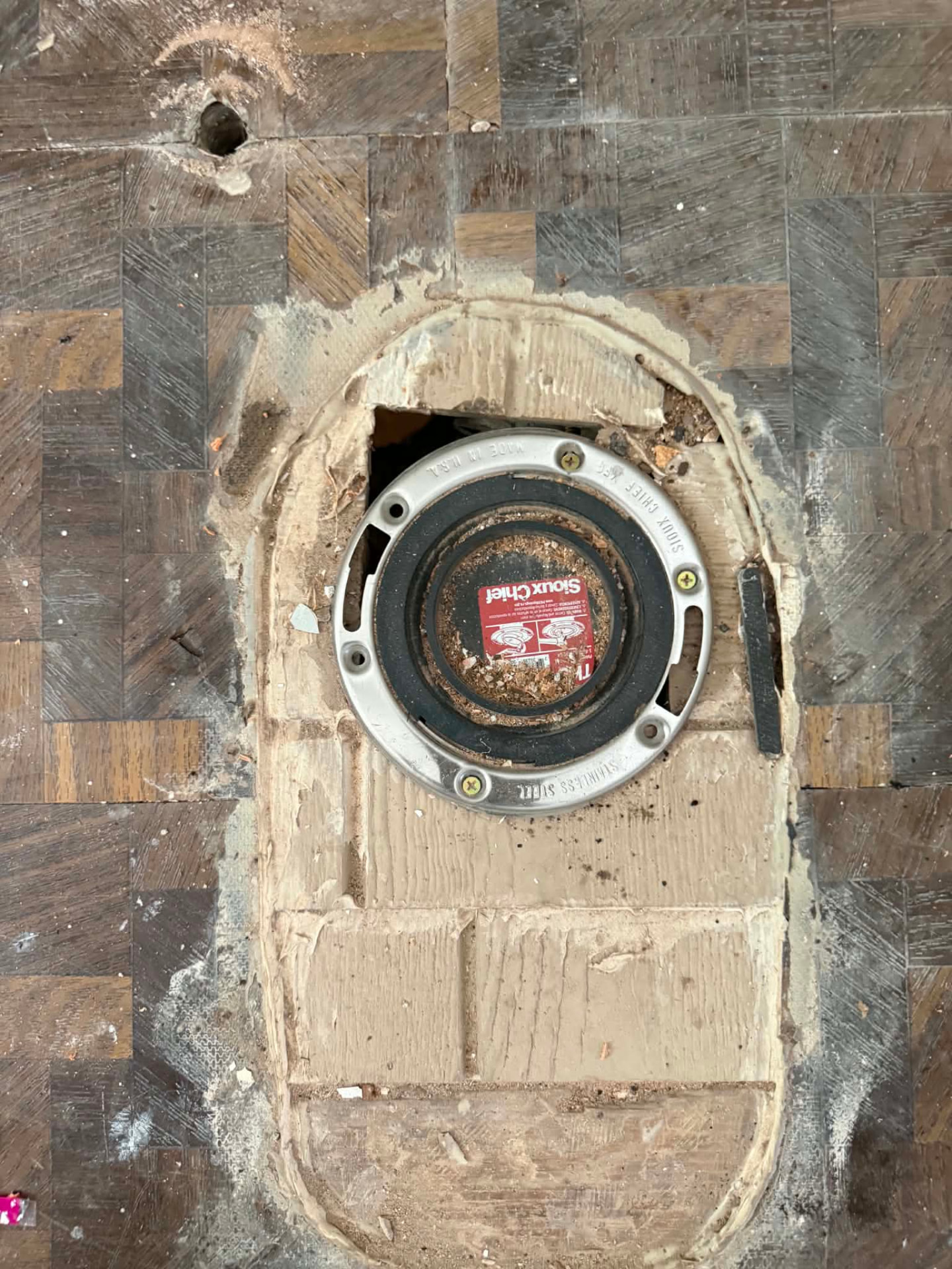 Toilet flange and closet drain access opened up in a subfloor for drain repair